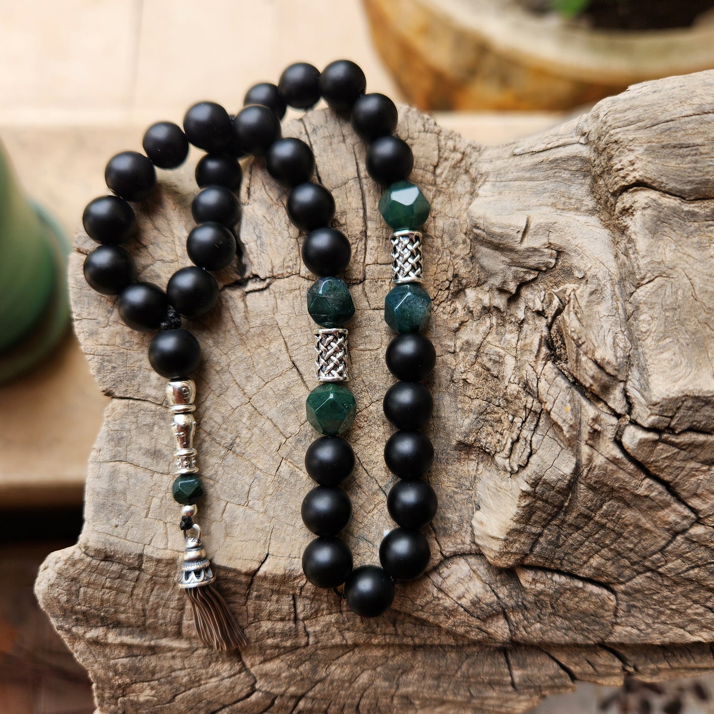 Black and green beaded misbaha on a wooden surface