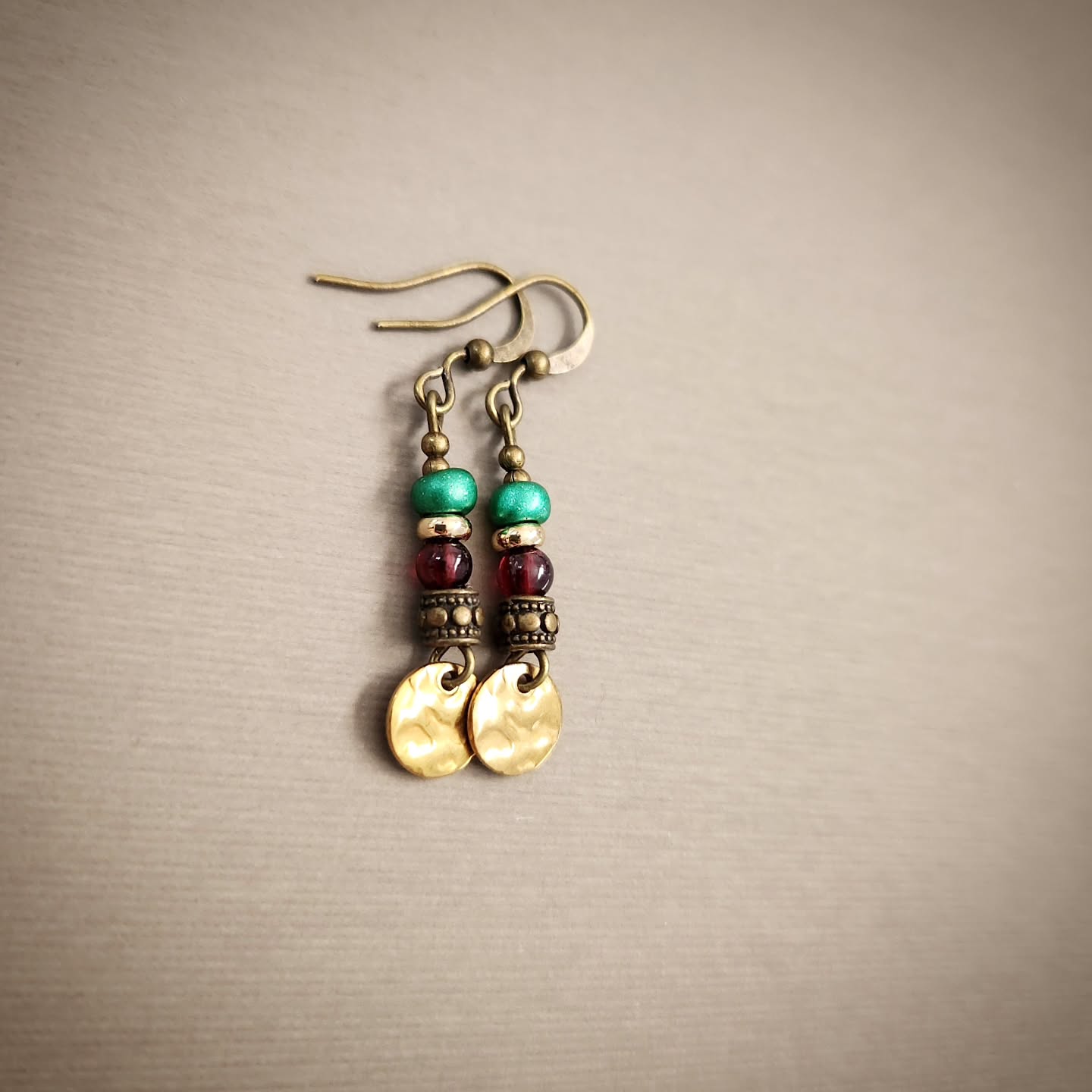 Pair of earrings with beads and gold accents on a beige background