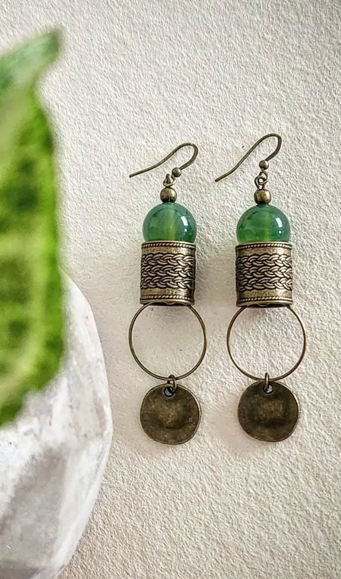 Pair of earrings with green beads and bronze accents on a light background
