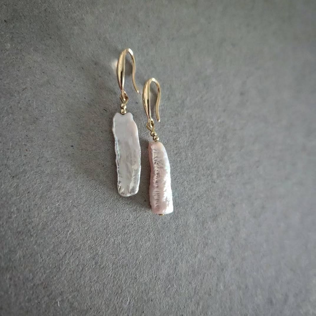 Pair of gold earrings with pearls on a gray background