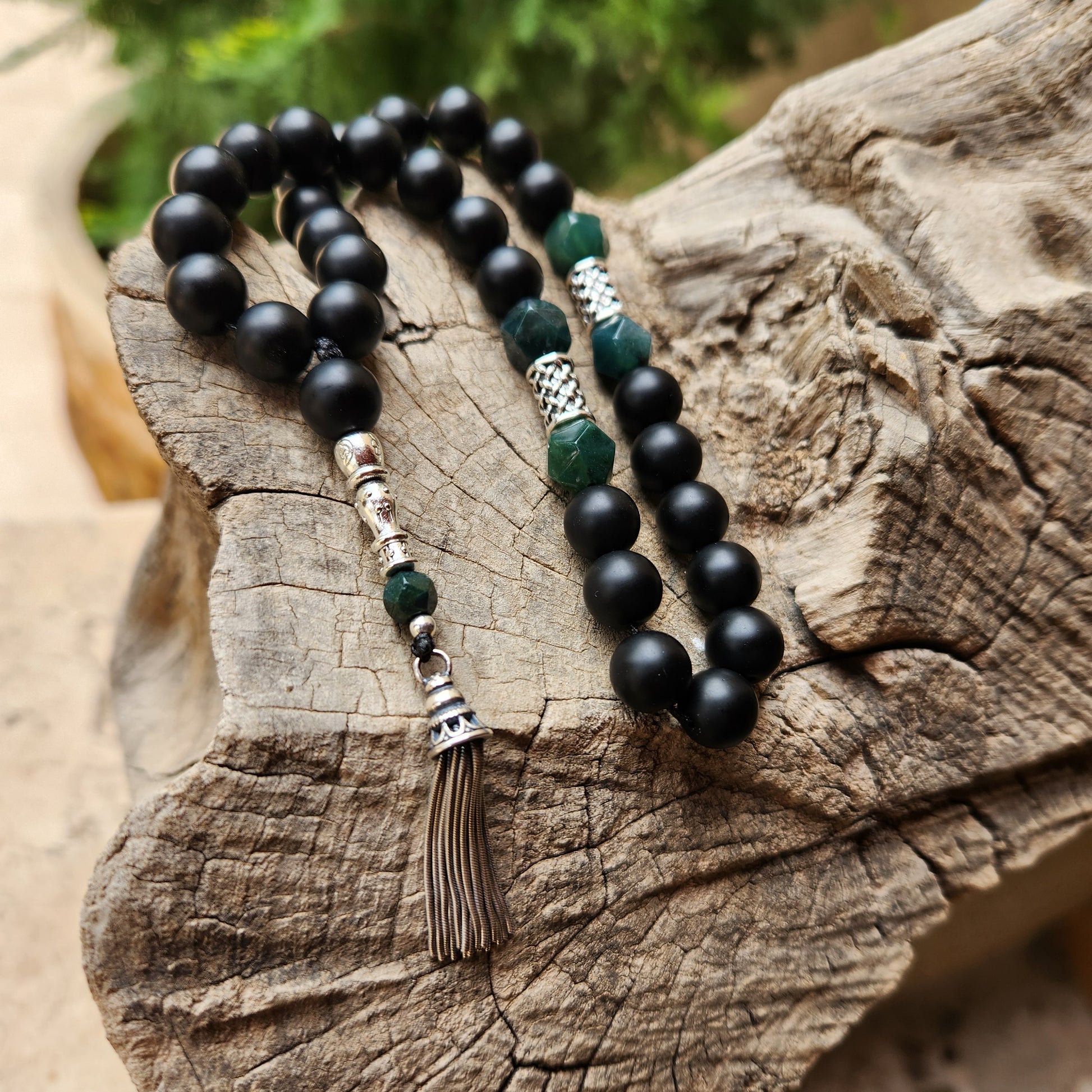 Black and green beaded misbaha on a wooden surface