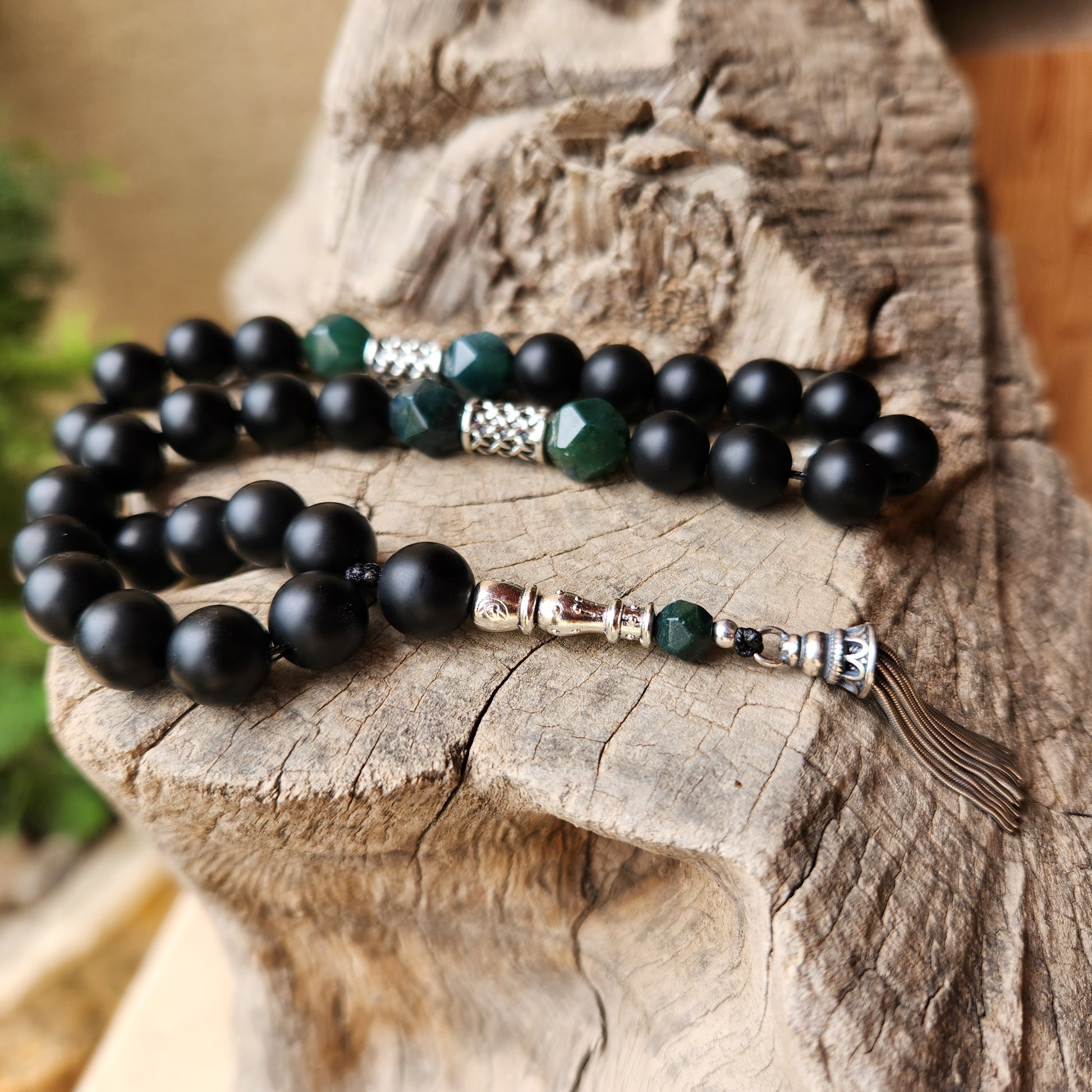 Black and green beaded misbaha on a wooden surface