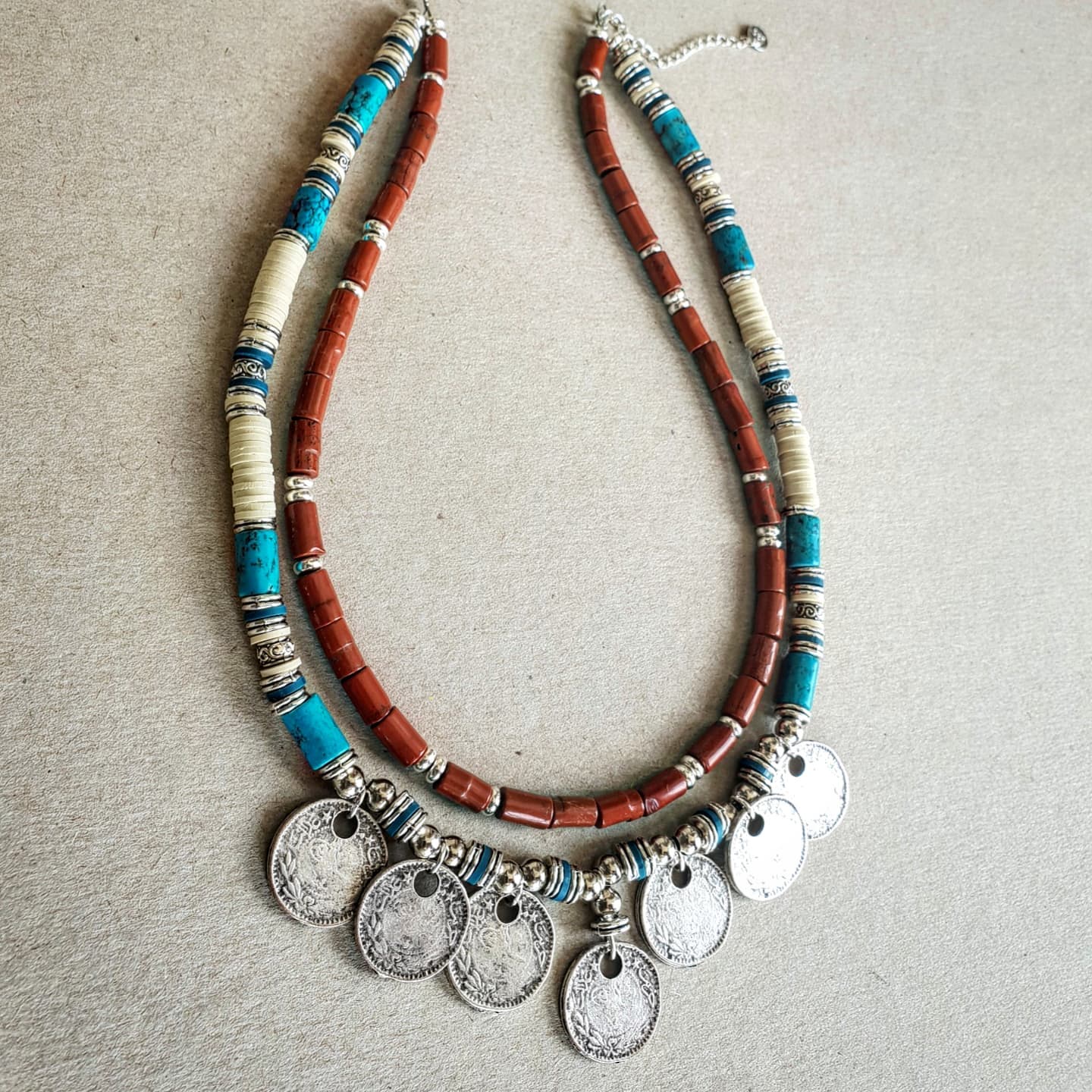 Necklace with beads and coins on a textured surface