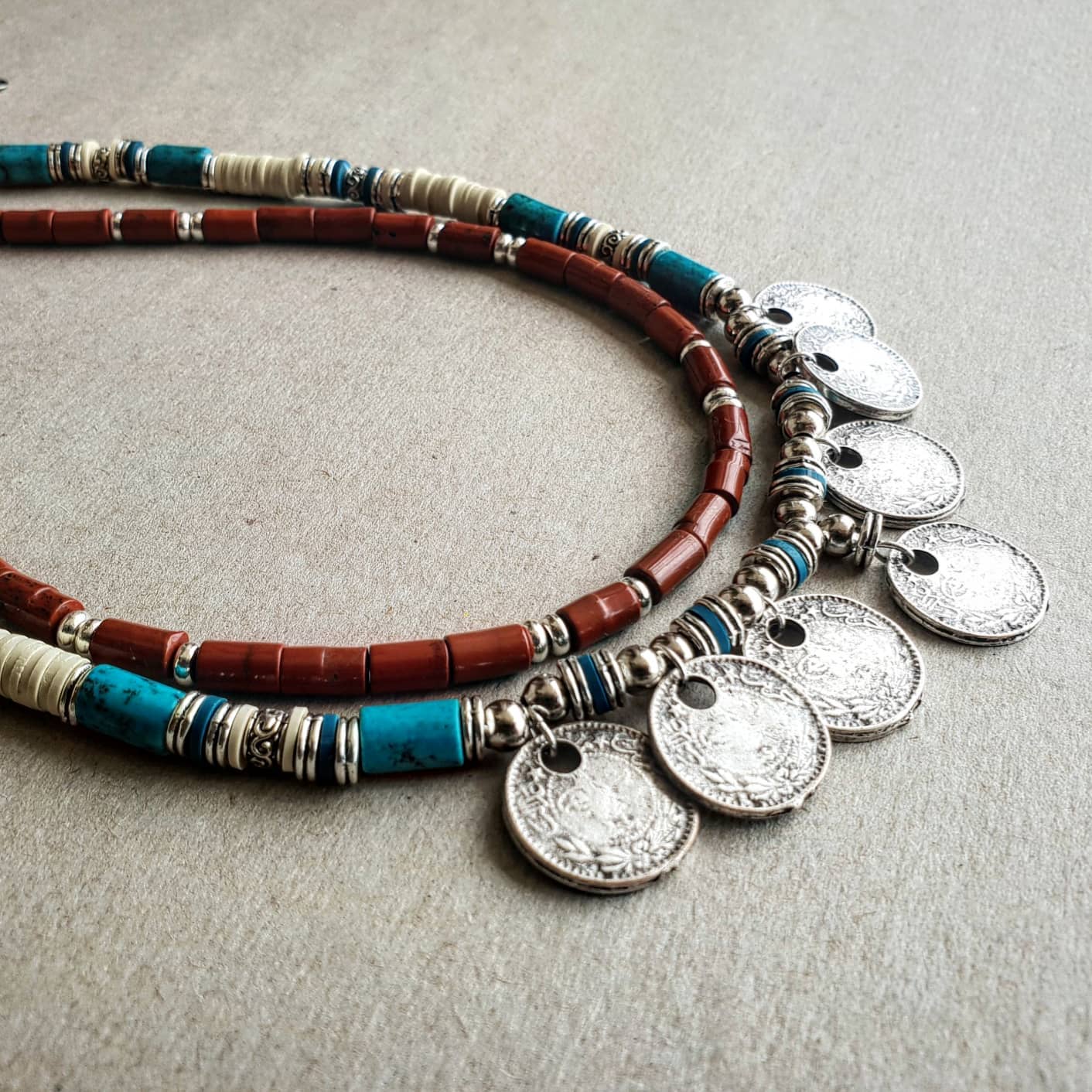 Necklace with beads and coins on a textured surface