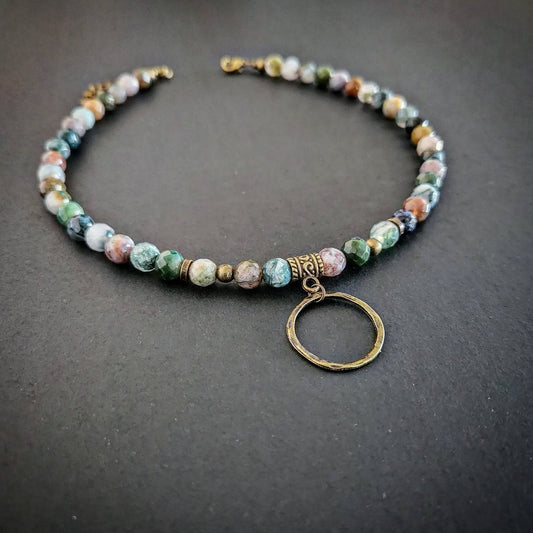 Necklace with bronze and multicolored beads and a circular pendant on a dark background