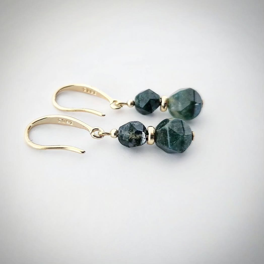 Gold earrings with green Moss Agate stones on a light gray background