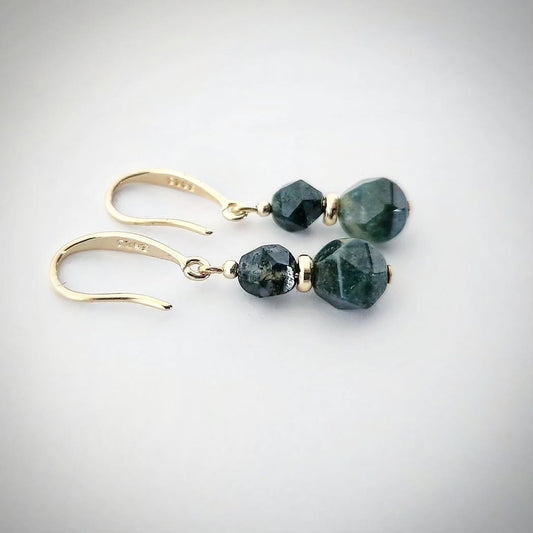 Gold earrings with green Moss Agate stones on a light gray background