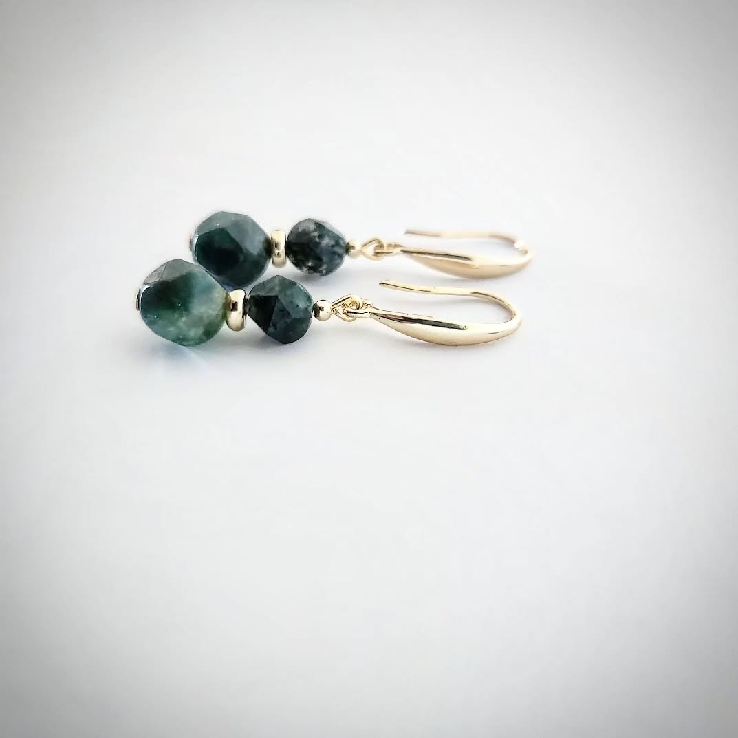 Gold earrings with green Moss Agate stones on a light gray background