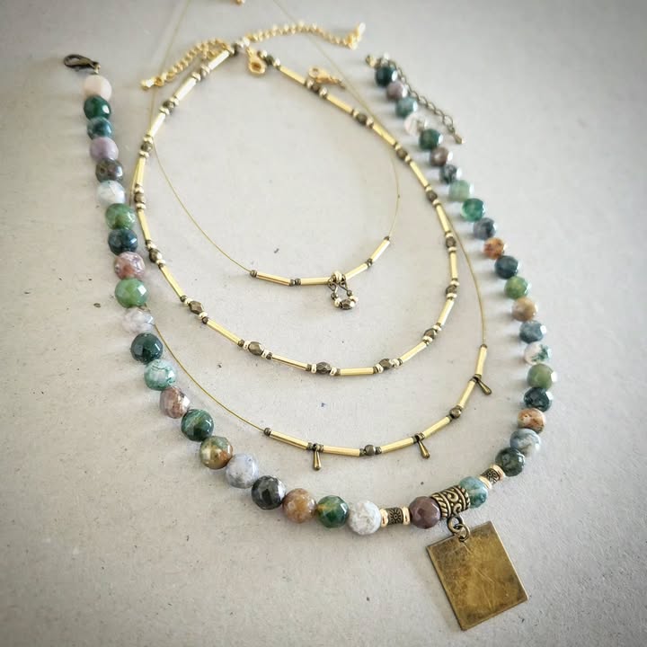Stack of beaded necklaces with gold accents on a textured surface