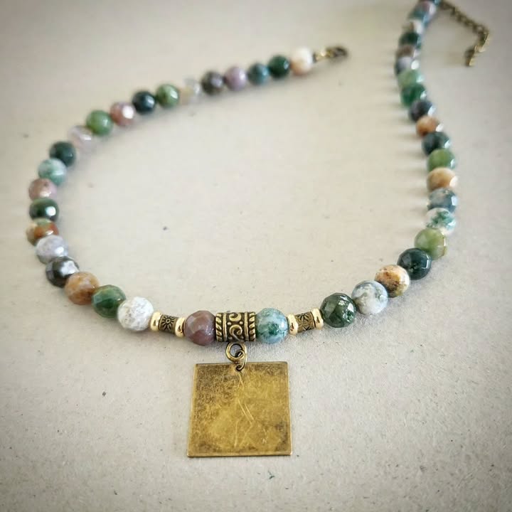 Necklace with bronze and multicolored beads and a rectangular pendant on a light gray background