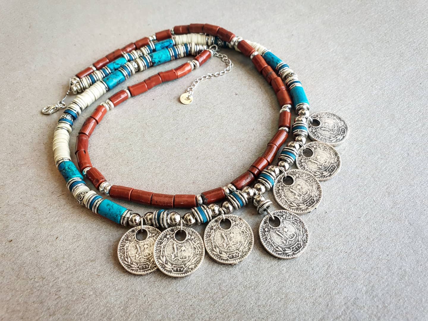 Necklace with beads and coins on a textured surface