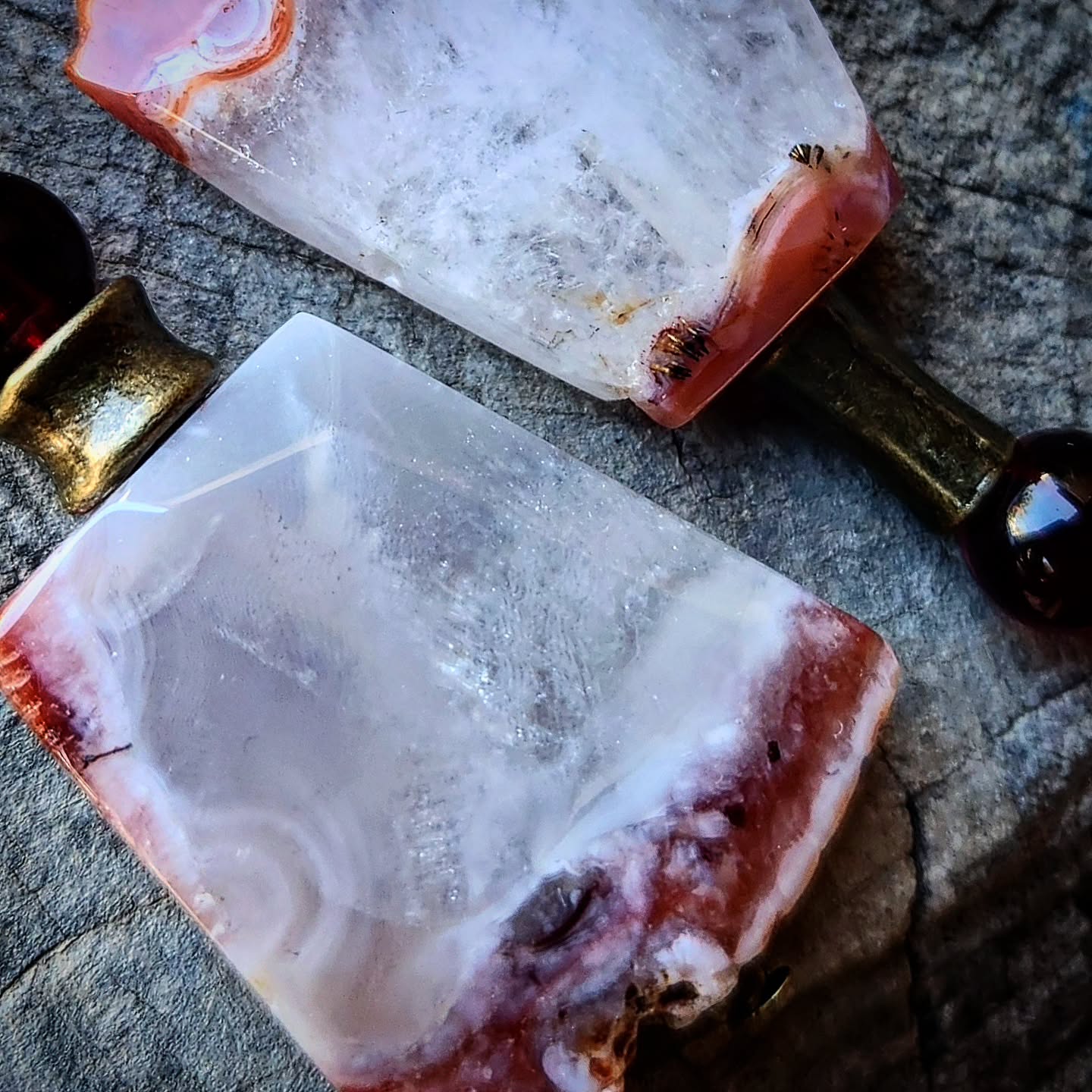 Pair of earrings with agate-like stones and garnet stones on a wooden surface