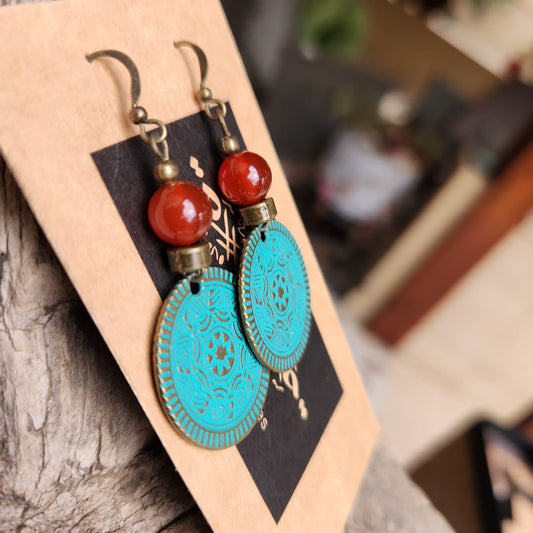 Turquoise earrings with red beads on a wooden stand