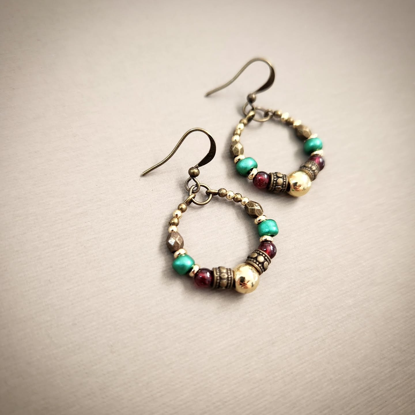 Pair of hoop earrings with colorful beads on a beige background
