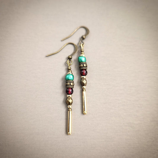Pair of beaded earrings with gold and colorful beads on a beige background