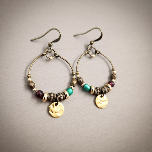 Pair of hoop earrings with beads and gold accents on a gray background
