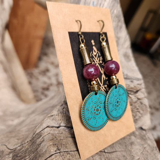 Pair of earrings with turquoise and red beads on a wooden stand.