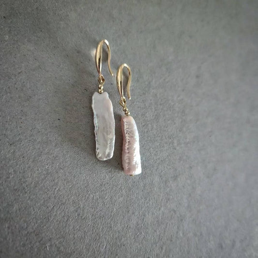 Pair of gold earrings with pearls on a gray background