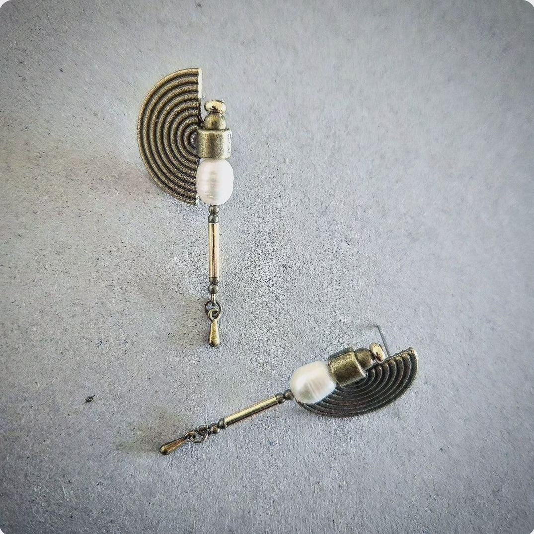 Pair of earrings with pearls on a textured gray surface