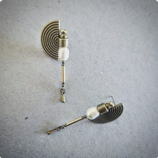 Pair of earrings with pearls on a textured gray surface