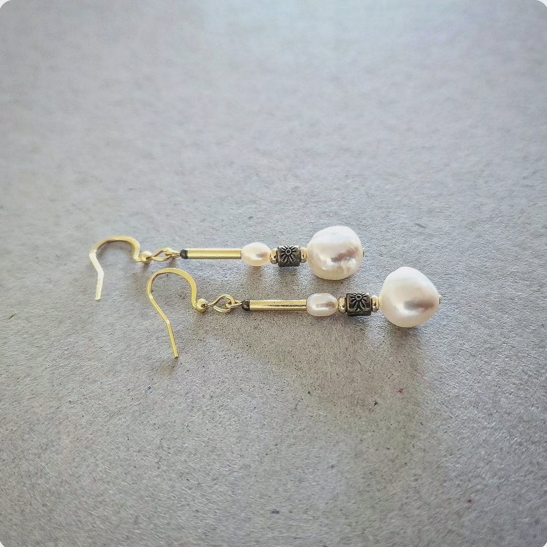 Pearl earrings with gold hooks on a gray surface
