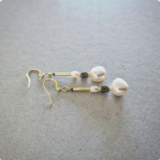 Pearl earrings with gold hooks on a gray surface