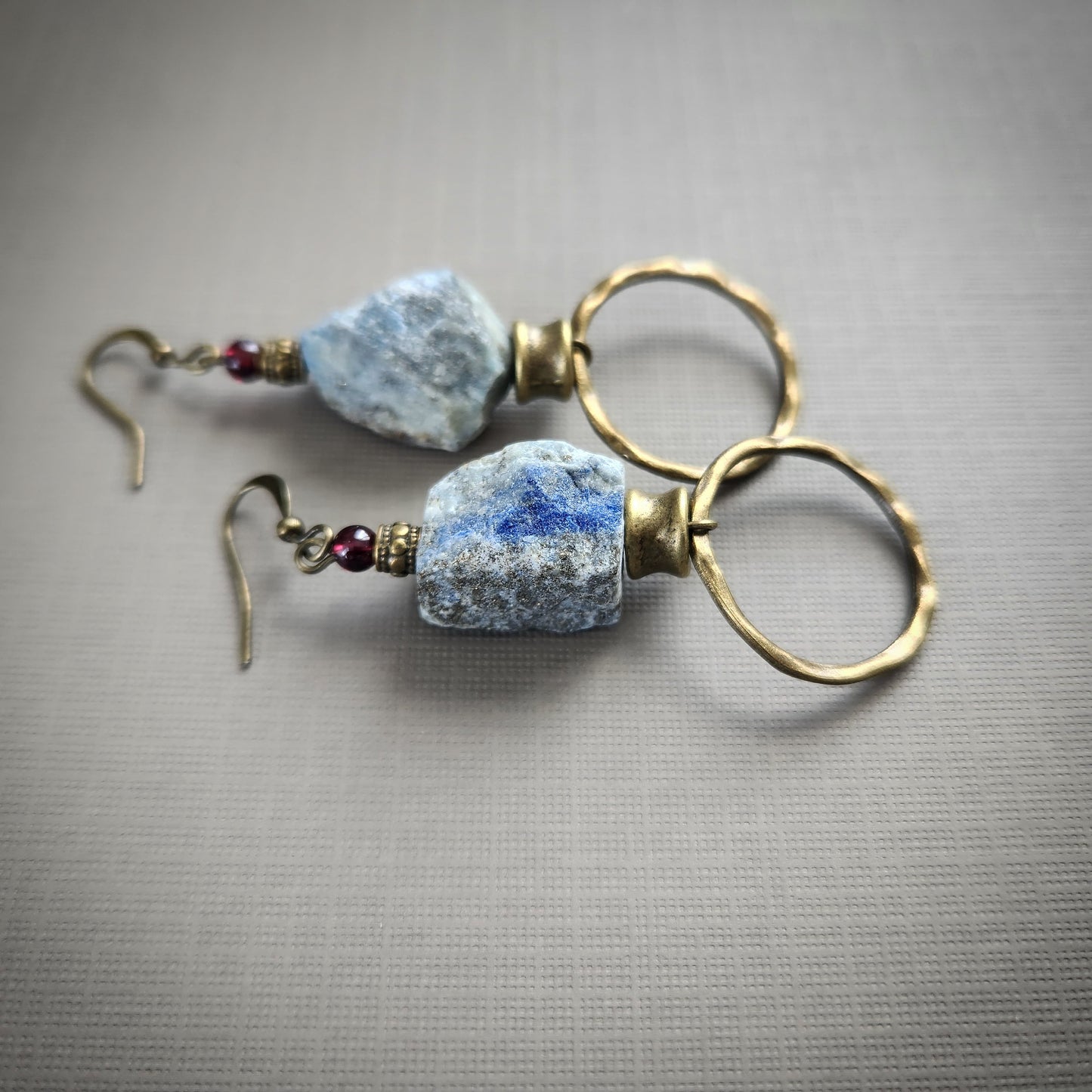 Pair of bronze earrings with blue stone beads on a gray background