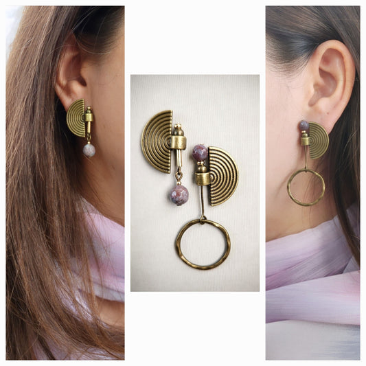 Bronze earrings with circular designs and pink stones worn by a person, displayed against a neutral background.