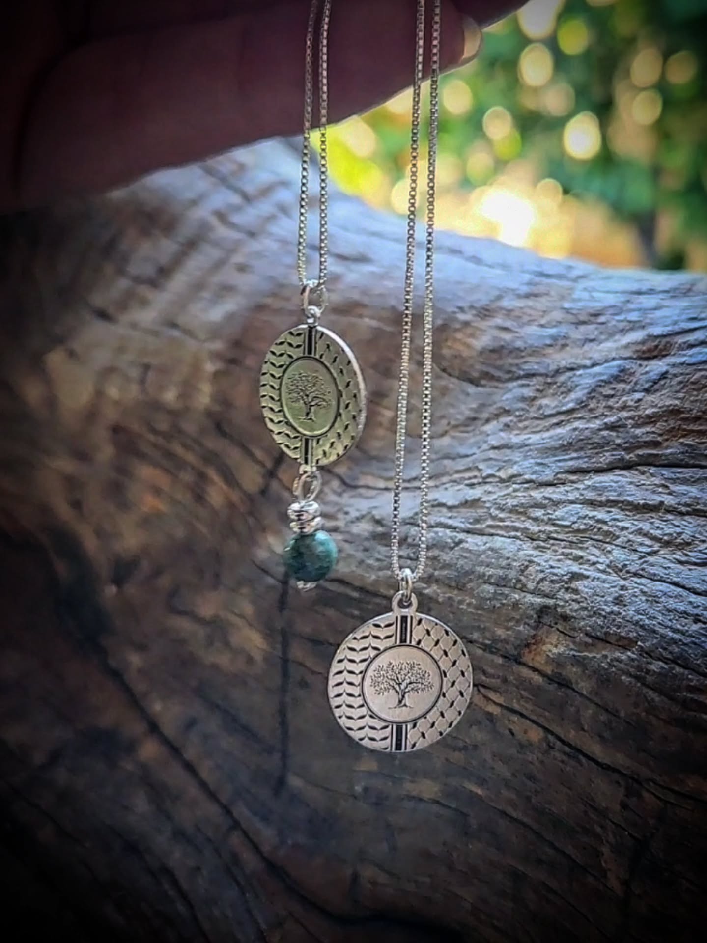 /Two necklace with circular pendants and a turquoise bead on a wooden surface
