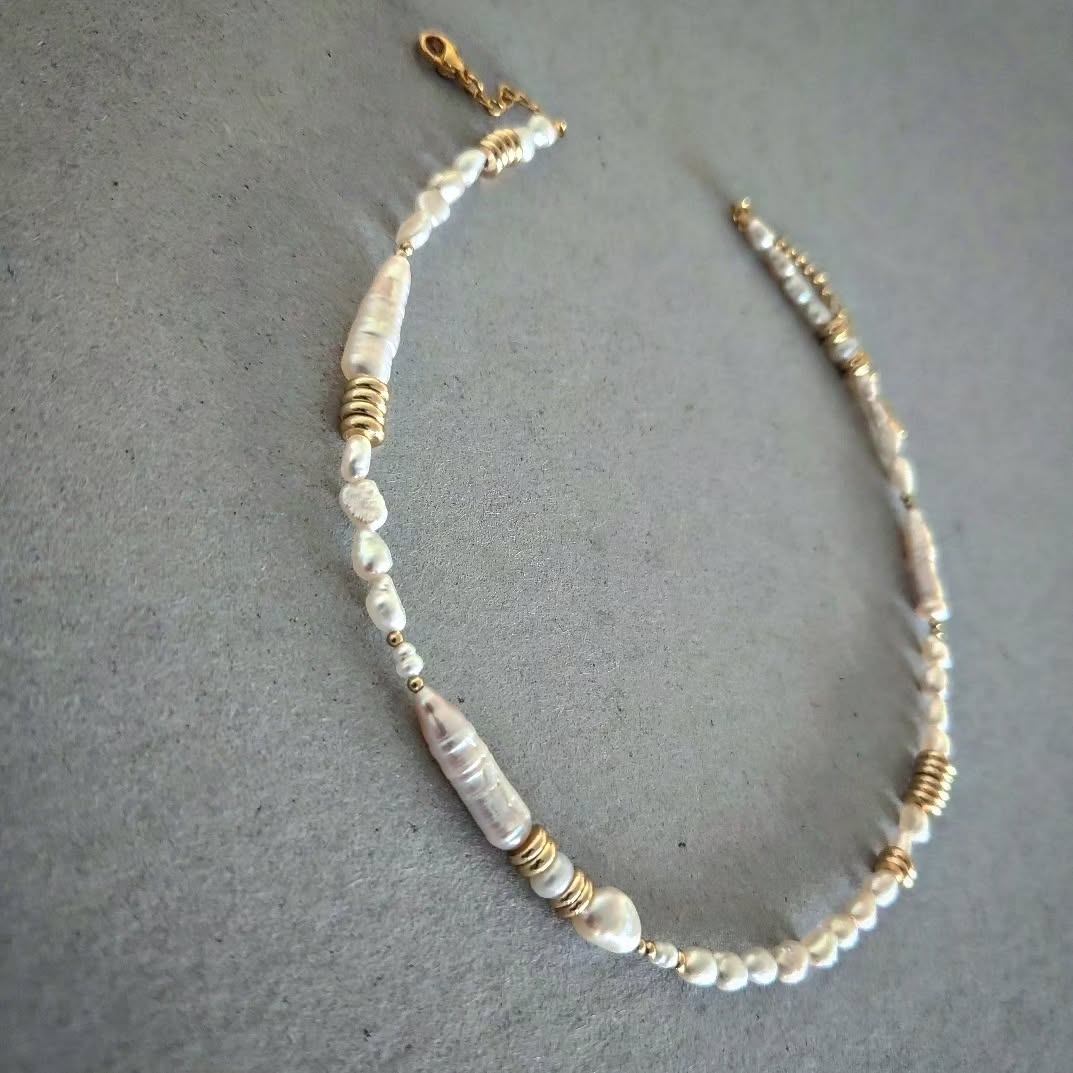 Necklace with pearls and gold accents on a gray background