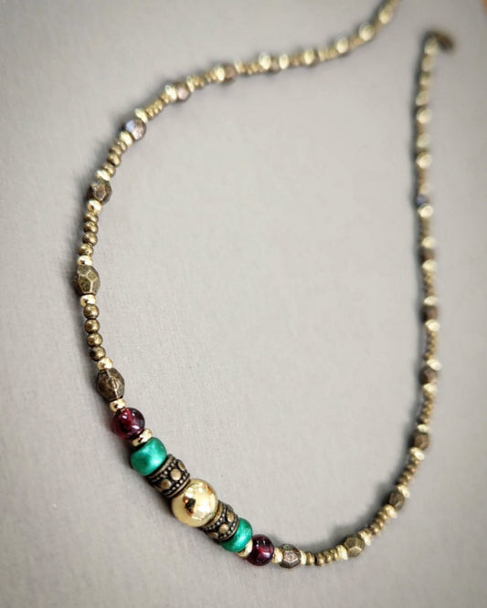 Bronze necklace with gold, red and turquoise beads on a gray background