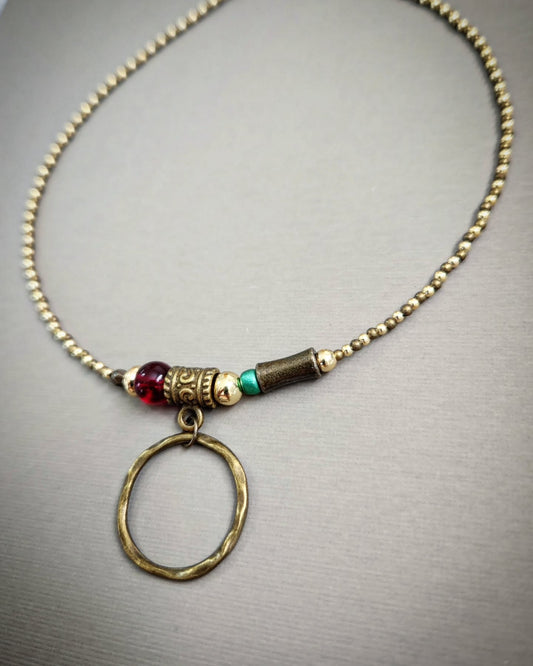 Bronze necklace with gold, red and turquoise beads on a gray background