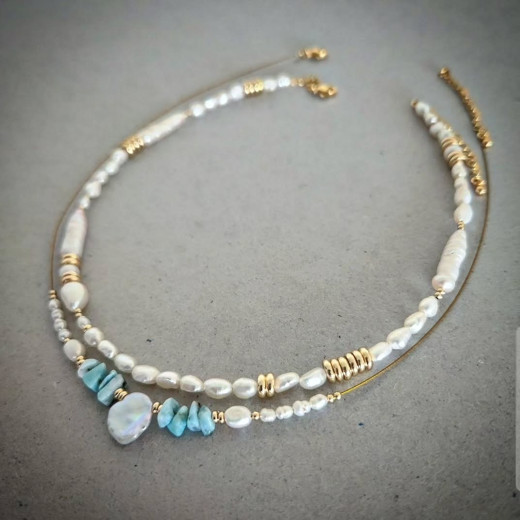 two necklace with pearls, gold accents, and one of them with turquoise stones on a gray background