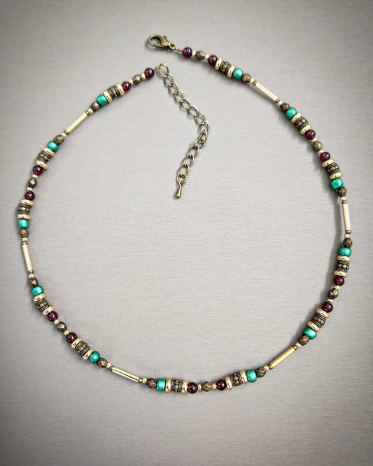 Bronze necklace with gold, red and turquoise beads on a gray background