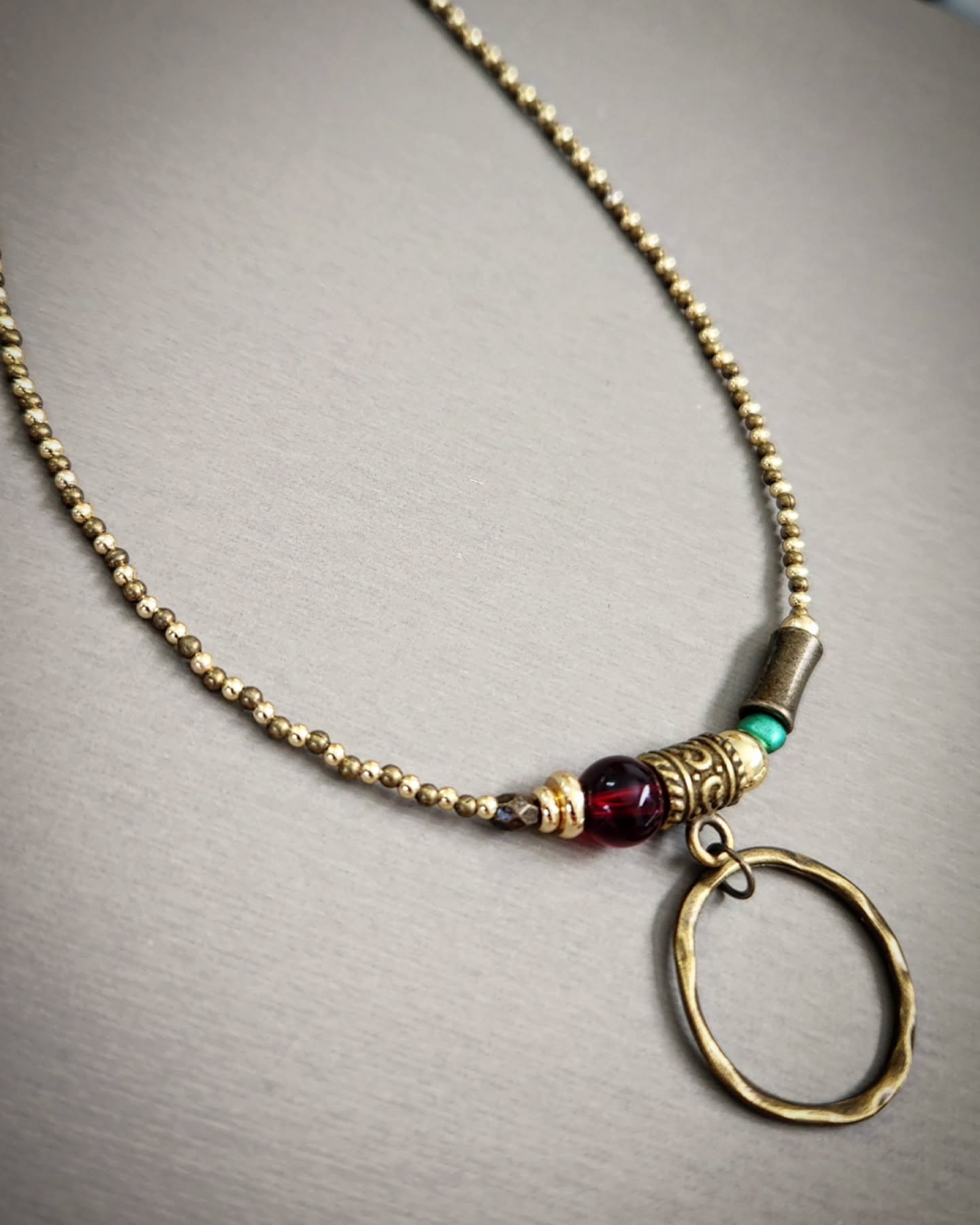 Bronze necklace with gold, red and turquoise beads on a gray background