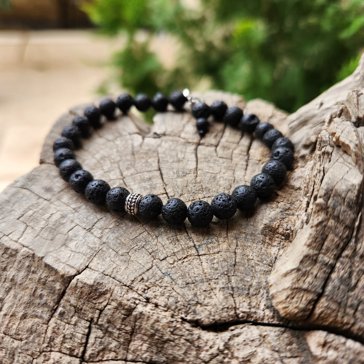 Black beaded bracelet on a wooden log with a natural background