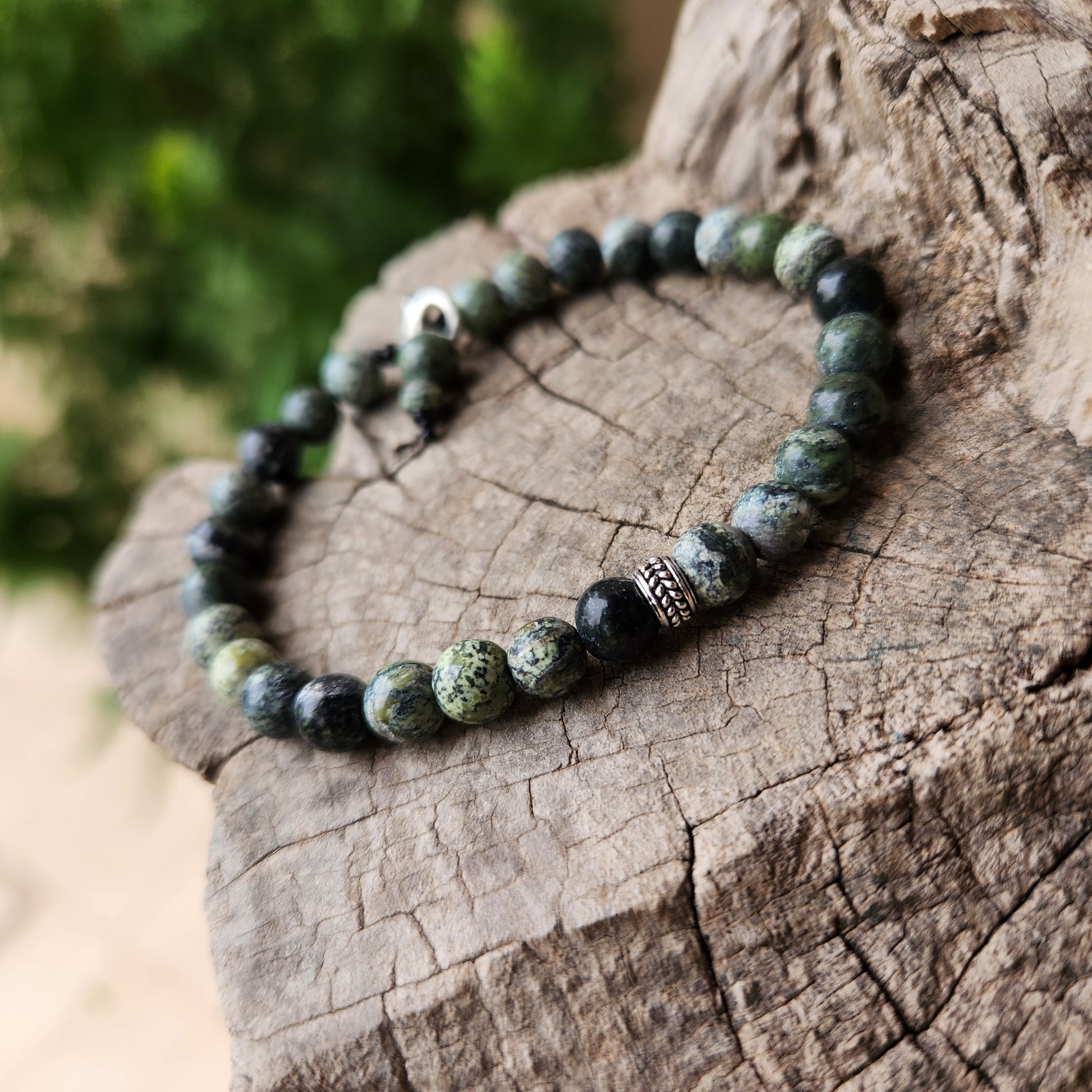 Beaded bracelet on a wooden surface with a blurred green background