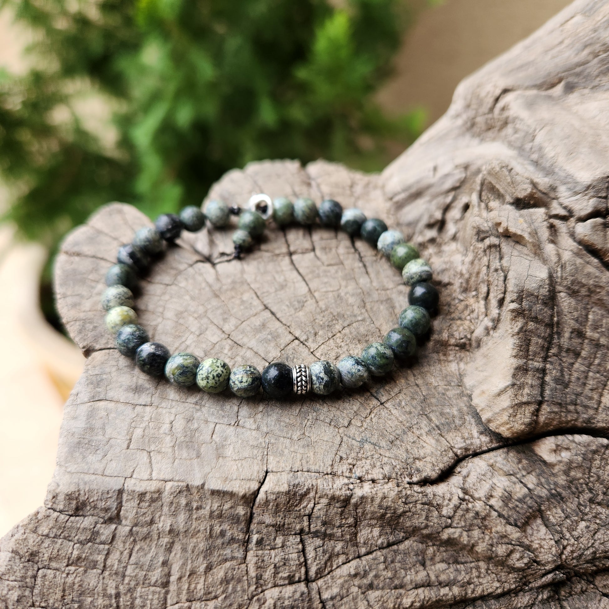 Beaded bracelet on a wooden surface with a blurred green background