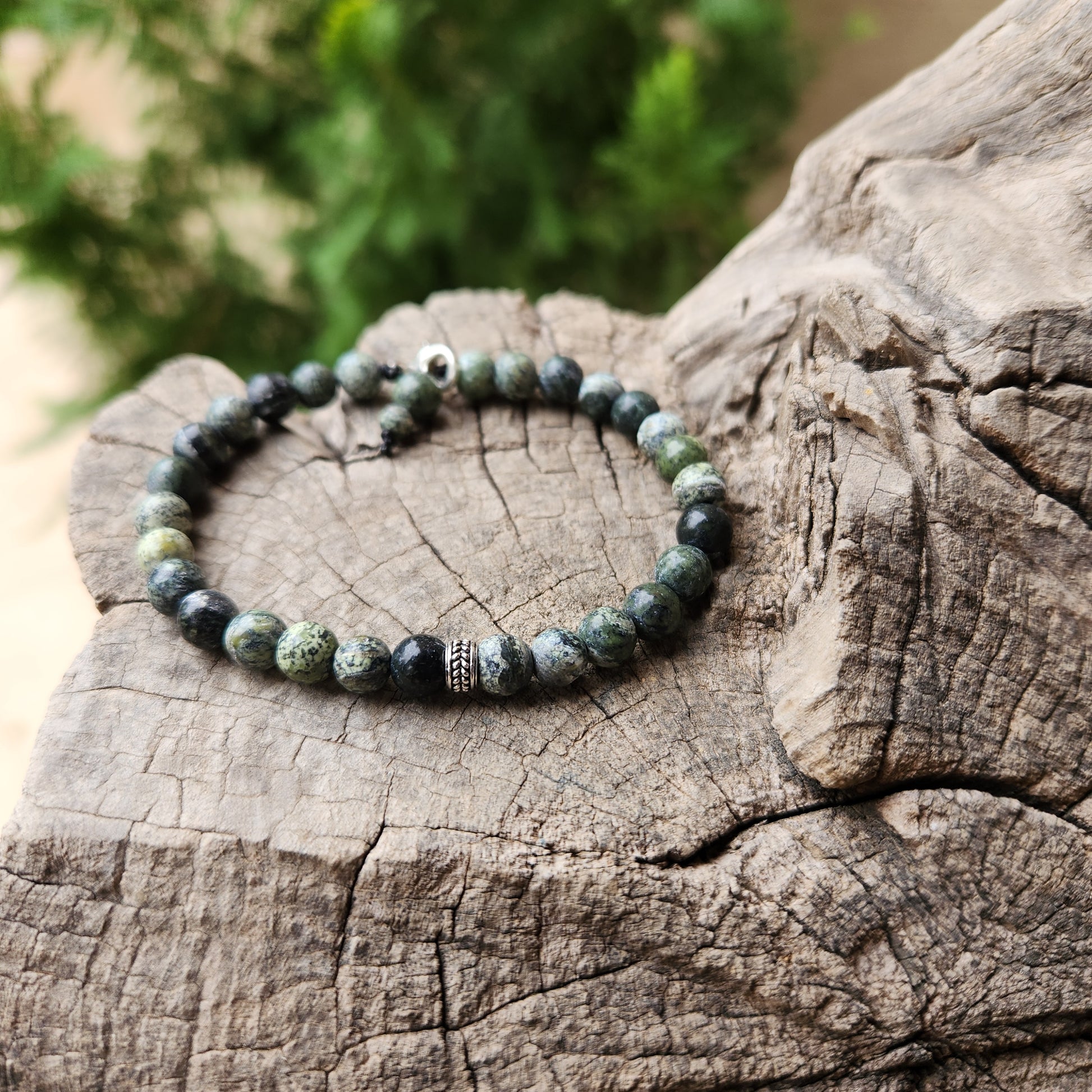 Beaded bracelet on a wooden surface with a blurred green background
