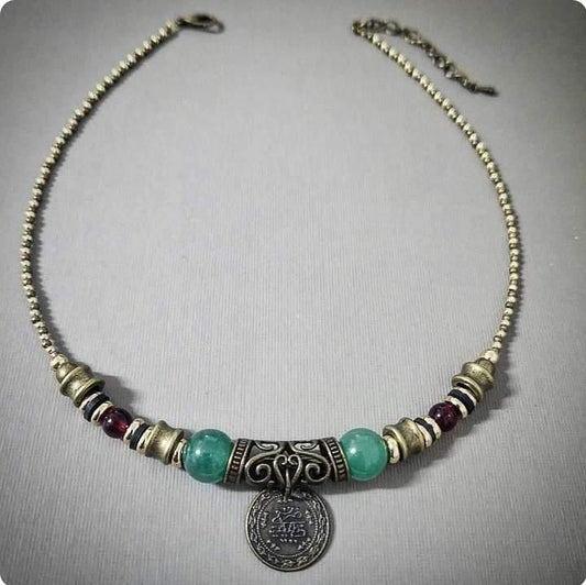 Necklace with gold and bronze beads and a coin pendant on a gray background
