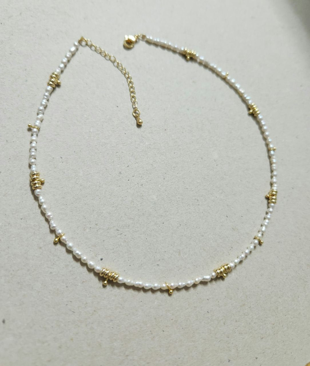 Necklace with pearl beads and gold accents on a light gray background