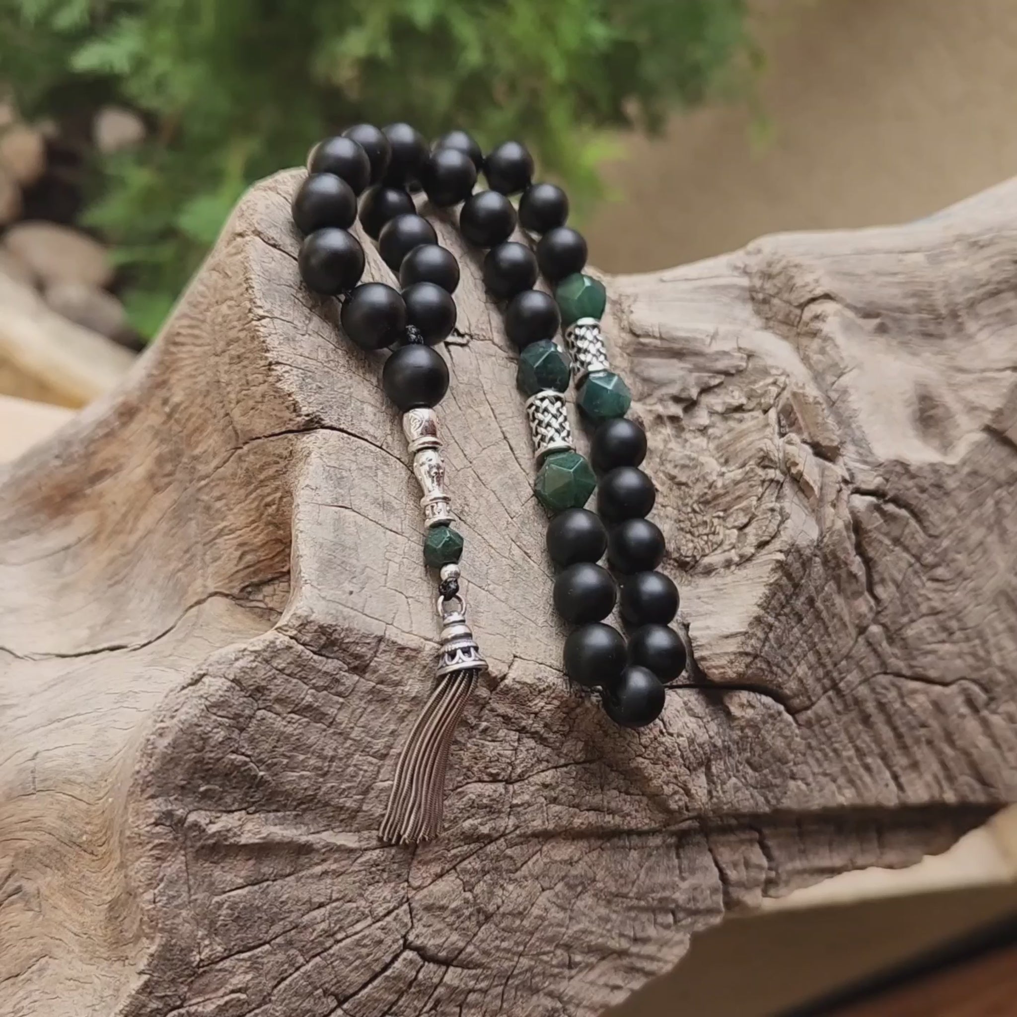 Black and green beaded misbaha on a wooden surface